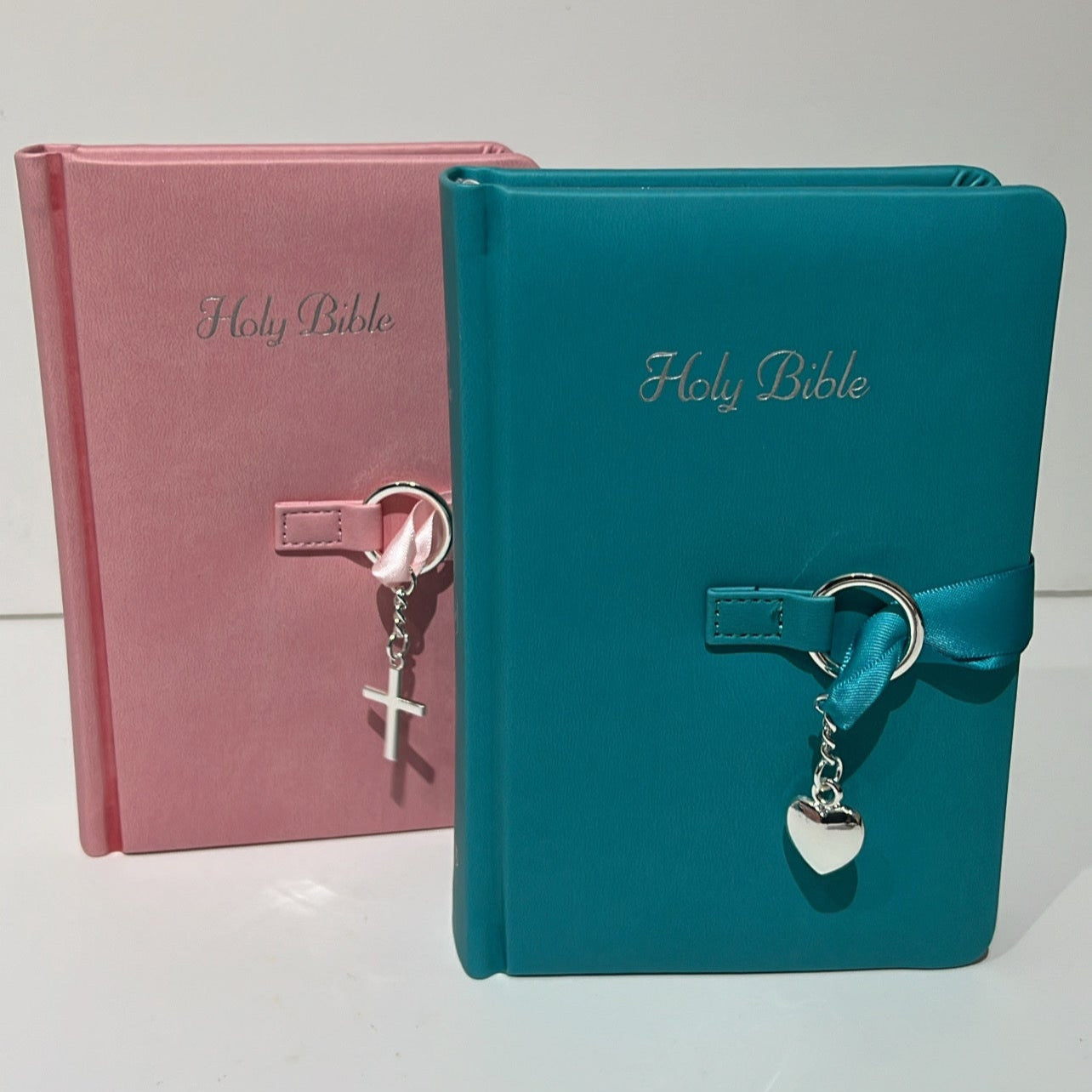 Two Bibles, one pink and one blue, with keychains on a white background